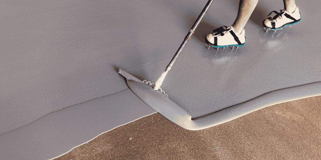 Application d'un sol en résine grise à la raclette avec chaussures à crampons à Pau