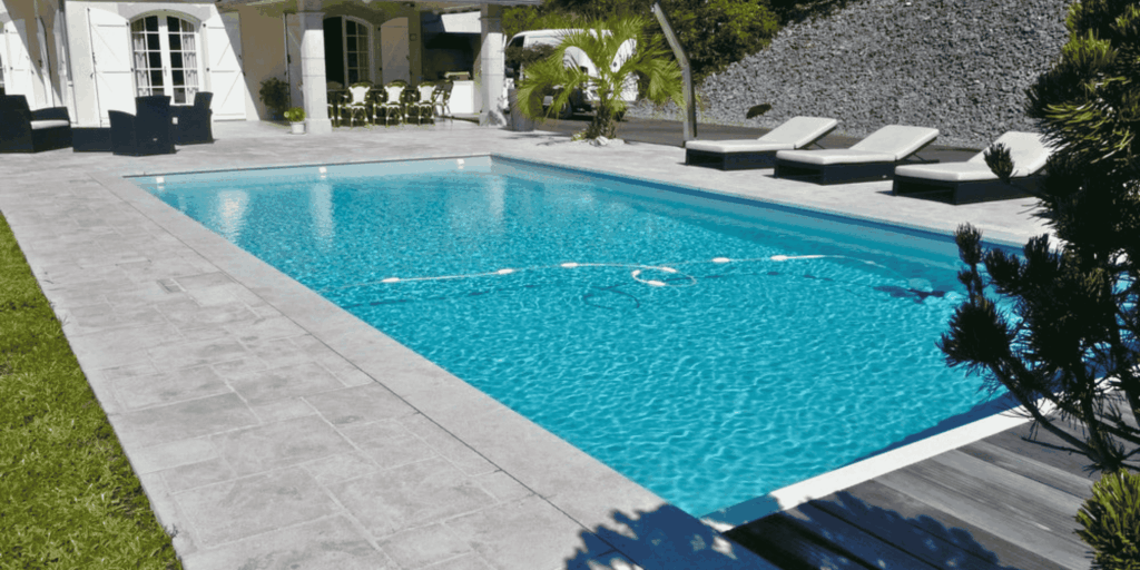 Dallage gris autour d'une piscine rectangulaire devant une maison à Pau