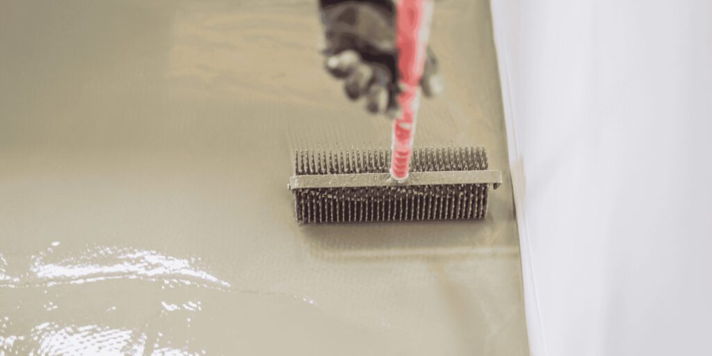 Débullage d'un sol en résine fraîche au rouleau à picots sur un chantier à Lescar