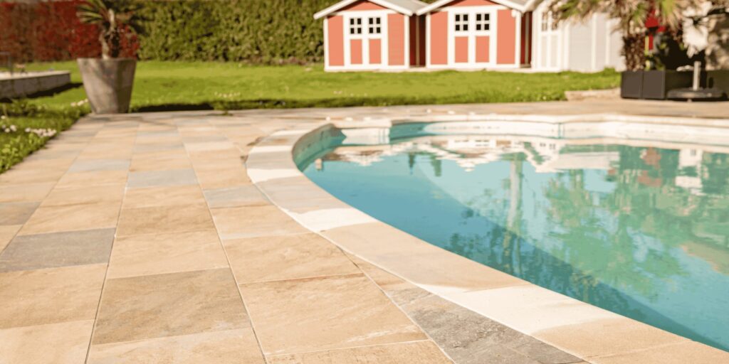 Margelles arrondies en pierre beige autour d'une piscine ovale à Serres-Castet