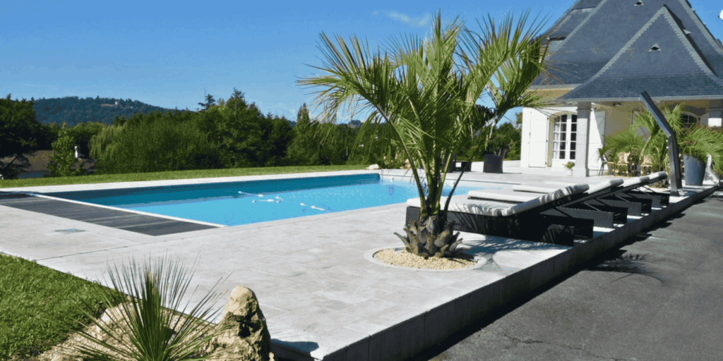 Plage de piscine habillée en pierre naturelle claire devant une villa à Serres-Castet