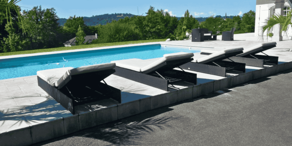 Plage de piscine carrelée avec transats face aux collines à Serres-Castet