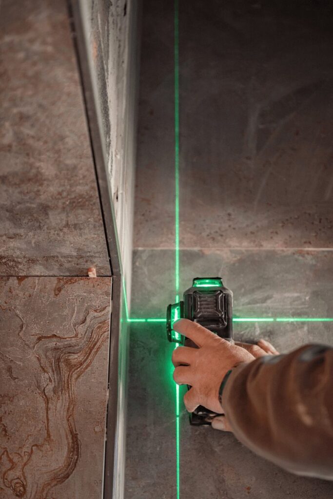 Carreleur alignant un carrelage mural au niveau laser sur un chantier à Lescar