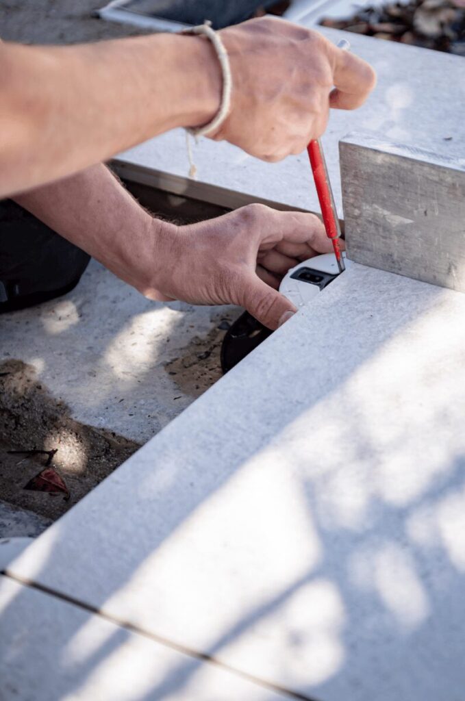 Carreleur traçant une coupe sur une dalle avant pose sur plots à Pau